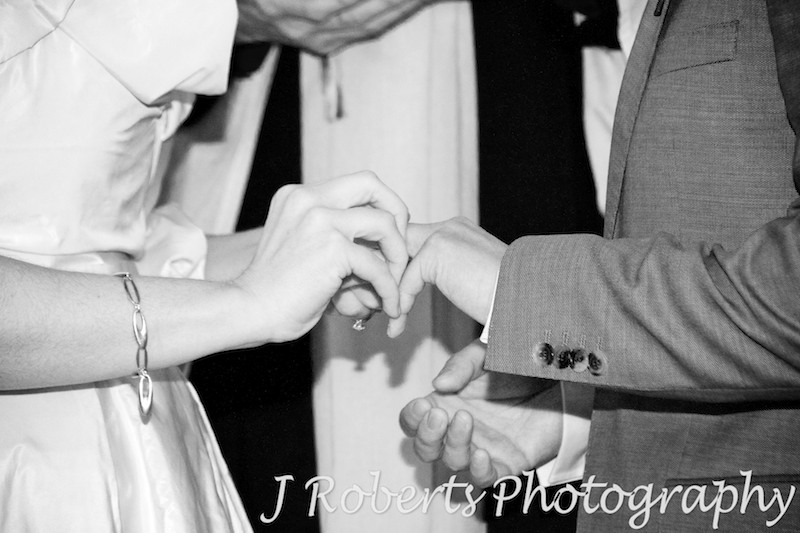 Bride putting ring on grooms finger - wedding photography sydney